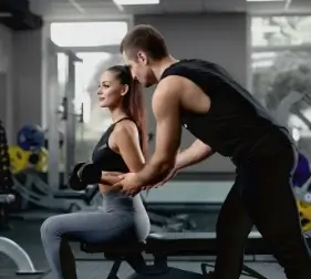 handsome-personal-instructor-helping-his-female-client-training-with-dumbbells (1)